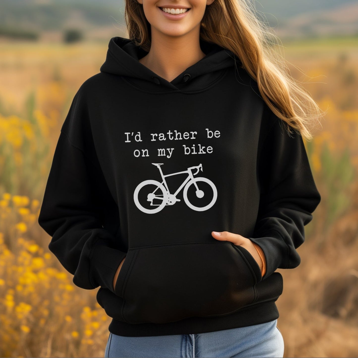 Woman wearing a black hoodie with a bicycle graphic and text in a field