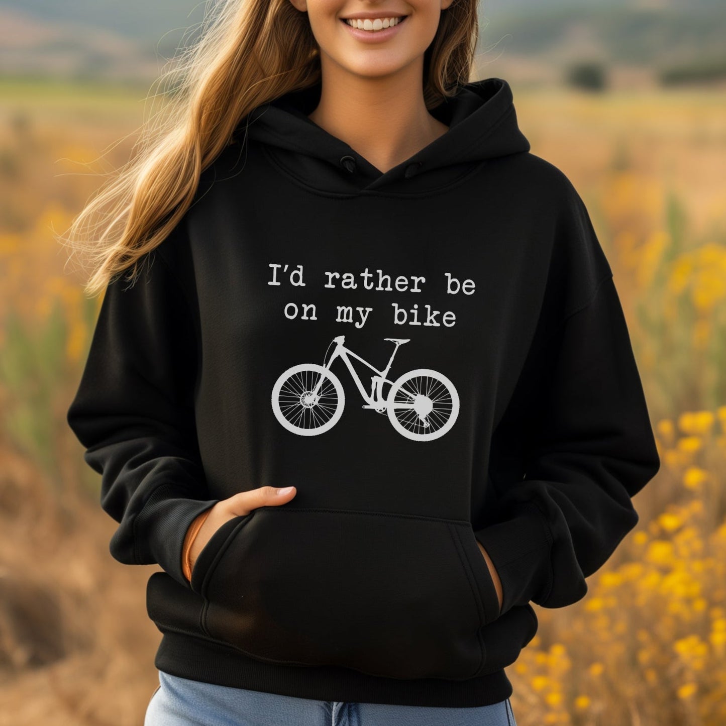 Woman wearing a black hoodie with a bicycle graphic and text in a field